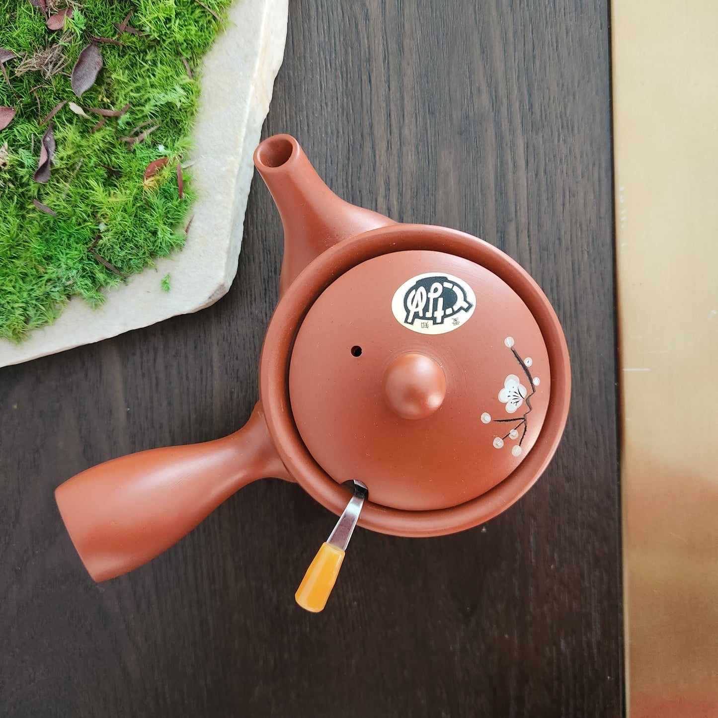 Red ceramic teapot with a lid on a dark wooden surface