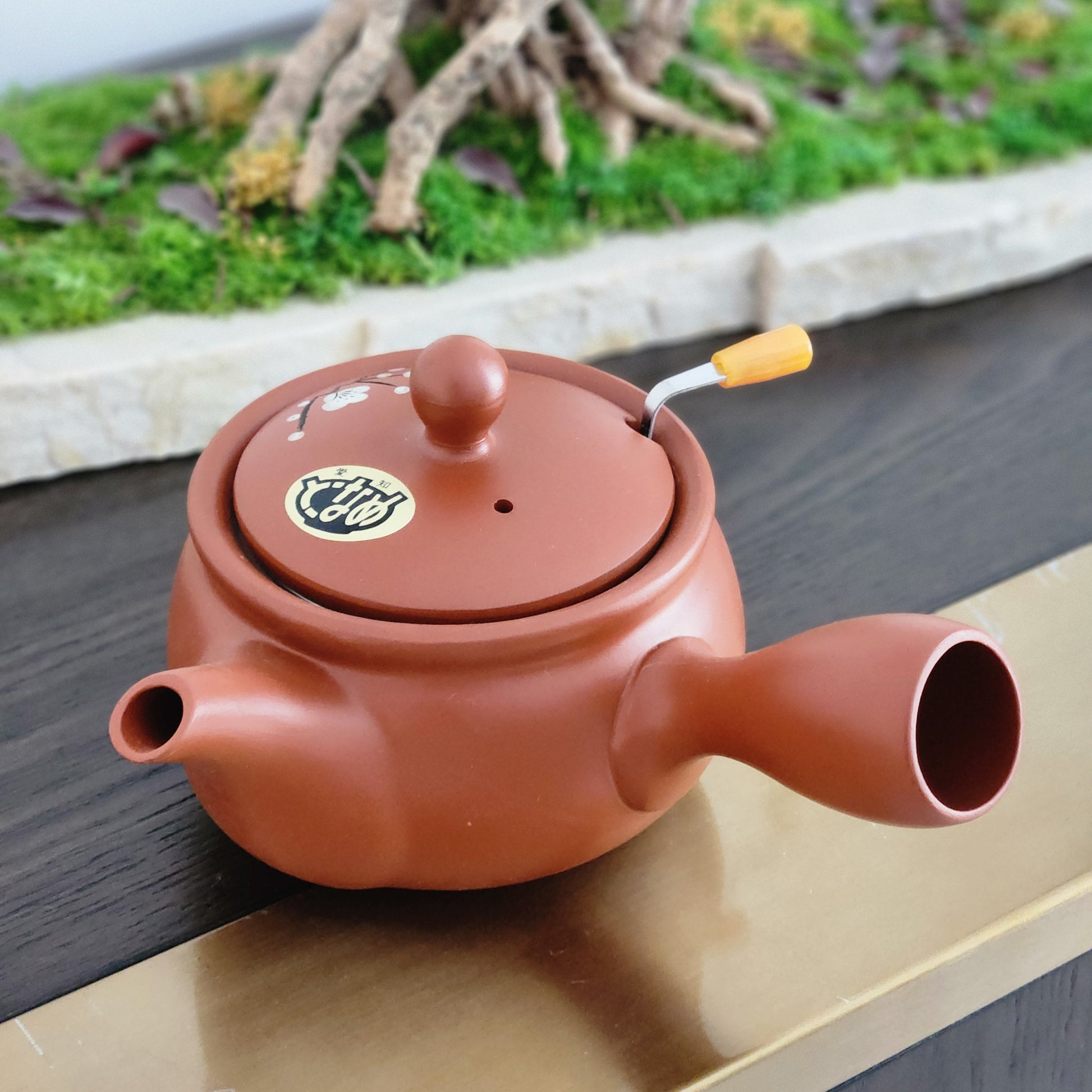 Red ceramic teapot with a lid on a wooden surface